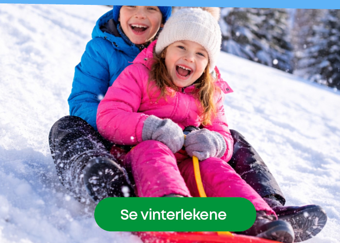 Barn som leker ute i snøen med akebrett i vinterferien